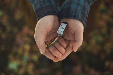 Two hands hold an electronic Faikin and cable.