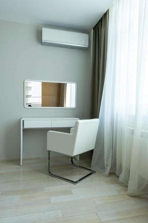 A wall mounted air conditioner unit is above a study desk and chair.