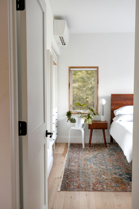 A wall mounted air conditioner unit is next to a bed in a master bedroom.