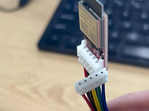 Close-up of a electronic connector with multicolored wires on a blurred keyboard background.