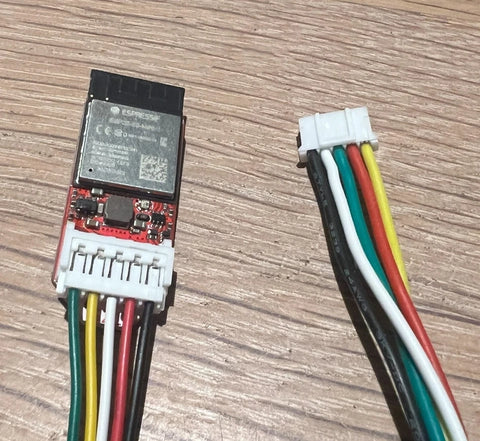 Faikin electronic component with connectors and multicolored wires on a wooden surface.
